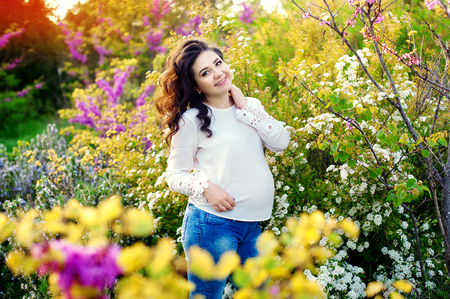 84961105 - pregnant woman standing in flowers